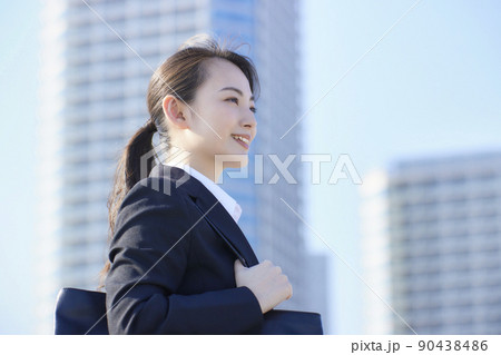 リクルートスーツの若い女性　青空　高層ビル　笑顔 90438486
