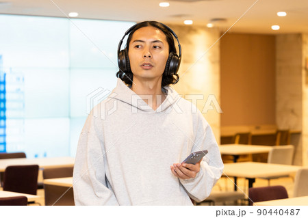 スマホの音楽を聴くヘッドフォンの男性 90440487