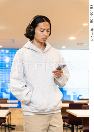 スマホの音楽を聴くヘッドフォンの男性 90440498