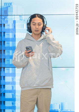 巨大モニターの前に立つヘッドフォンの男性 90442759