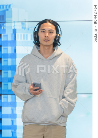 巨大モニターの前に立つヘッドフォンの男性 90442764