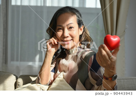 Charming asian senior retired aged woman holding a red heart shape. Healthcare medical Charming asian senior retired aged woman holding a red heart shape. Healthcare medical 90443943