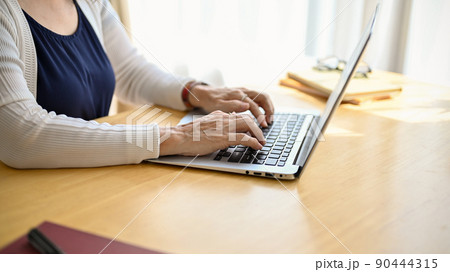 Cropped image of an asian middle aged woman using portable computer. Cropped image of an asian middle aged woman using portable computer. 90444315