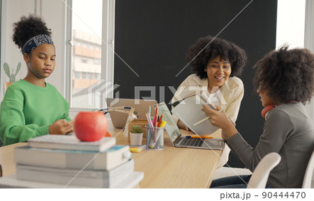 Classroom with diverse learners of happily African American students and teacher doing activities together. The teacher is teaching, guiding and talking to the children in diverse. 90444470