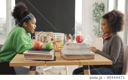 African American students talking happily while sharing with thoughts in study room. 90444471