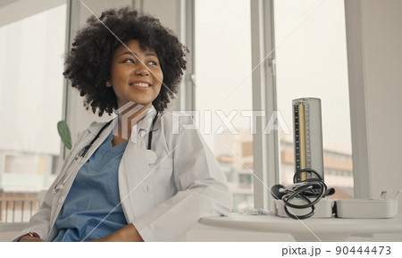 Portrait of a smiling female doctor wearing a white coat with a stethoscope in a hospital office. 90444473