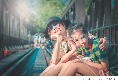 Mother and child is sitting the historical bridge of World War 2 in River Kwai. Kanchanaburi Thailand. Mother and child is sitting the historical bridge of World War 2 in River Kwai. Kanchanaburi Thailand. 90444843