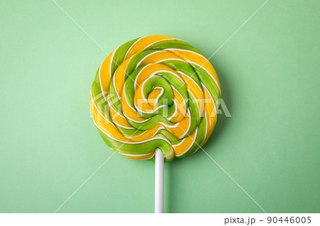 Brightly colored candy on a stick. Green background 90446005