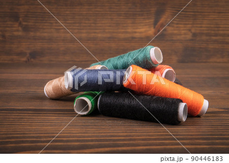 Thread spools on a brown wooden background Thread spools on a brown wooden background 90446183