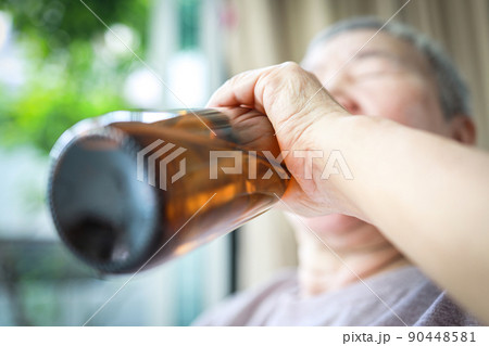 Elderly people with alcoholic drink,drunken,asian senior woman drinking beer from bottle,suffering from alcoholism,health problems,liver disease,alcohol dependence syndrome,alcohol addiction concept 90448581