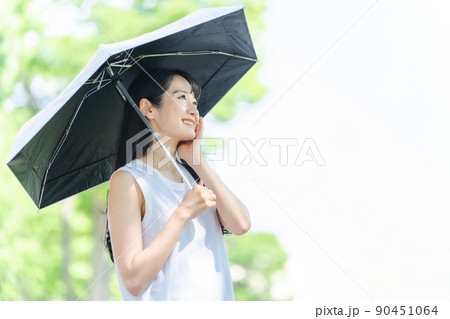 日傘をさしてUVケアする女性（笑顔・肌） 90451064