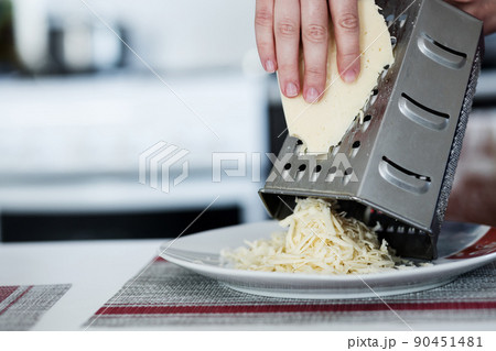 Woman grating cheese Woman grating cheese 90451481