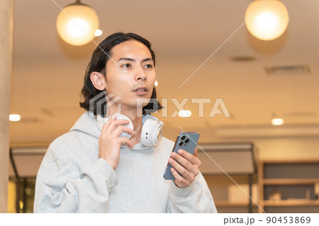 スマホを持つヘッドフォンの男性 90453869