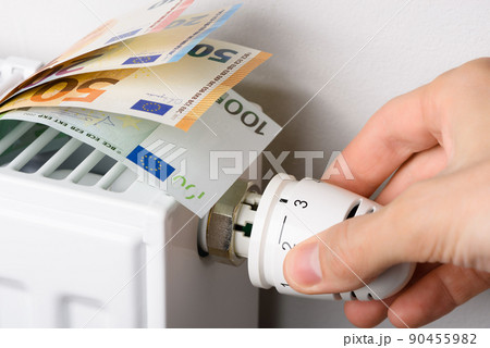 Hand adjusting the valve knob of heating radiator temperature thermostat with of euro money 90455982