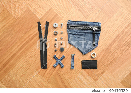 Flat lay composition with garment accessories and cutting details for jeans on table 90456529