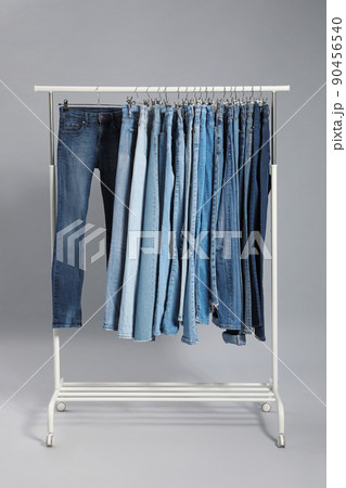 Rack with different jeans on grey background Rack with different jeans on grey background 90456540