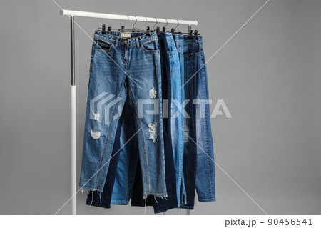 Rack with different jeans on grey background 90456541