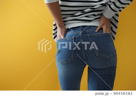 Woman wearing jeans on yellow background, closeup Woman wearing jeans on yellow background, closeup 90456582