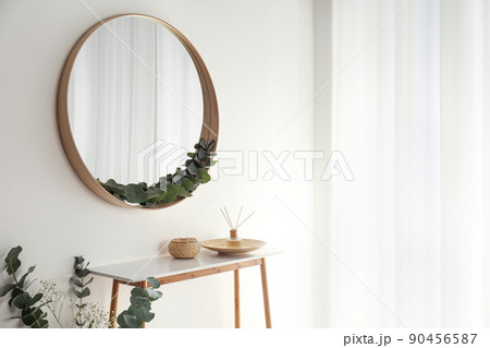Round mirror with wooden frame in light room Round mirror with wooden frame in light room 90456587