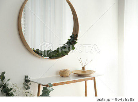Round mirror with wooden frame in light room 90456588