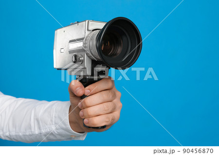 Man with vintage video camera on light blue background, closeup of hand Man with vintage video camera on light blue background, closeup of hand 90456870