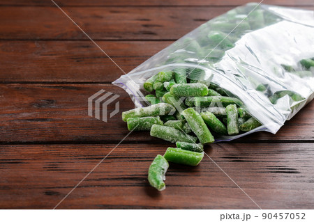 Frozen cut green beans on wooden table. Vegetable preservation Frozen cut green beans on wooden table. Vegetable preservation 90457052