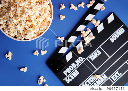 Tasty pop corn and clapboard on blue background, flat lay Tasty pop corn and clapboard on blue background, flat lay 90457151