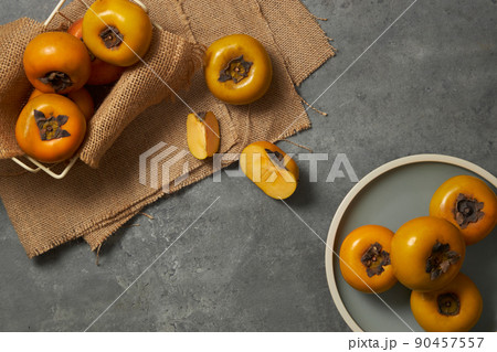 Top view of a light blue napkin of persimmon , green leaf in grey background for food advertising  90457557