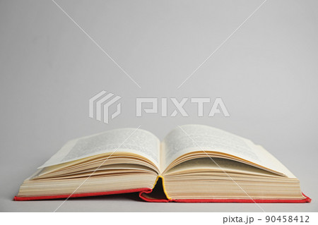 Open old hardcover book on light grey background. Space for text 90458412