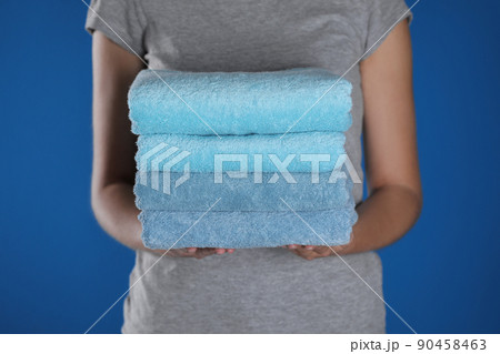 Woman holding fresh towels on blue background, closeup 90458463