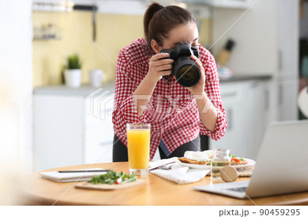 Food blogger taking photo of her lunch at wooden table indoors Food blogger taking photo of her lunch at wooden table indoors 90459295