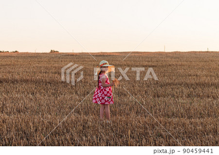 Child girl in straw hat dress in wheat field. Smiling kid in sunglasses sunset countryside. Cottagecore style aesthetic. 90459441