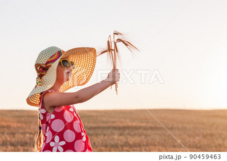Child girl in straw hat dress in wheat field. Smiling kid in sunglasses sunset countryside. Cottagecore style aesthetic. Child girl in straw hat dress in wheat field. Smiling kid in sunglasses sunset countryside. Cottagecore style aesthetic. 90459463