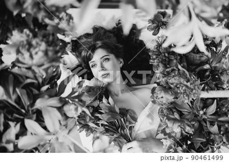 a beautiful and gentle young woman lies in peony flowers. feminine beauty. a beautiful and gentle young woman lies in peony flowers. feminine beauty. 90461499