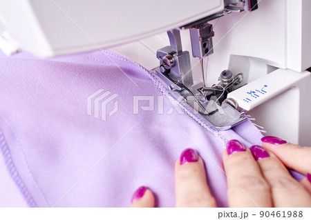 Woman overstitches a dress on an overlocker 90461988