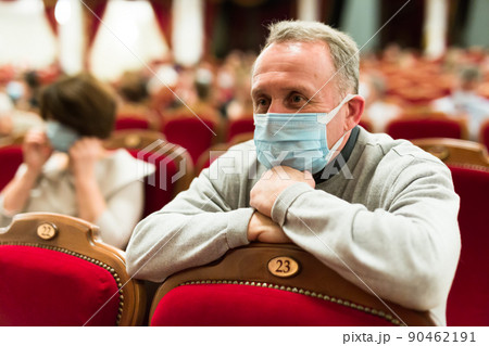 mature man in antivirus mask in theater watching a performance 90462191