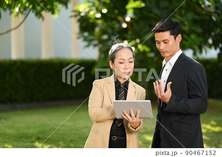 Successful business people in formalwear talking while walking on street in modern city Successful business people in formalwear talking while walking on street in modern city 90467152