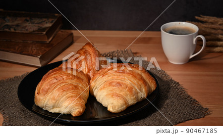 Fresh baked croissant and coffee on wooden table. Levitation, bread bakery products cafe concept Fresh baked croissant and coffee on wooden table. Levitation, bread bakery products cafe concept 90467185