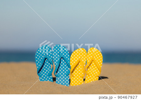 Multicolor flip-flops on the sandy baech against sea and sky 90467927