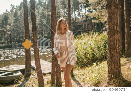 Cheerful stylish female strolling by the water Cheerful stylish female strolling by the water 90469734
