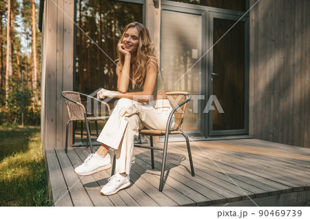 Pretty lady resting in the armchair on the wooden porch 90469739