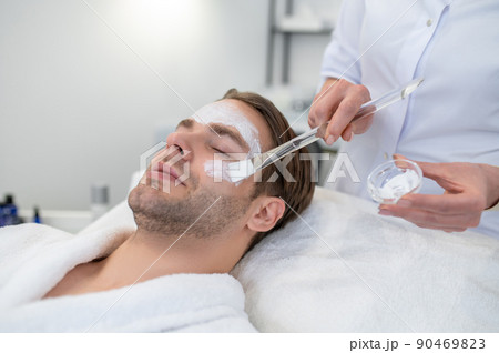 Cosmetologist applying cream on clients face with a brush Cosmetologist applying cream on clients face with a brush 90469823