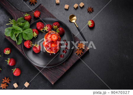 Cottage cheese pancakes with sliced strawberries and strawberry jam on a plate on a concrete background 90470327