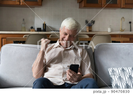 Excited senior male grandpa celebrate success looking on cell screen 90470830