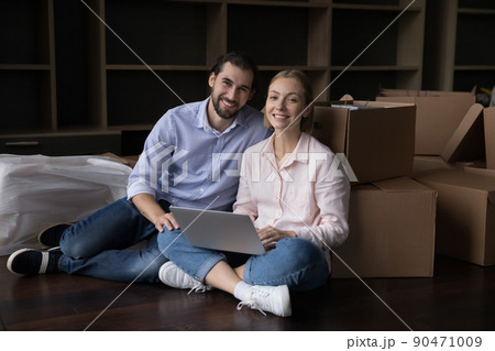 Enthusiastic millennial homeowners couple use laptop on moving day 90471009