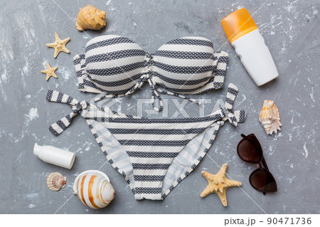 Woman swimwear and beach accessories flat lay top view on colored background Summer travel concept. bikini swimsuit, straw hat and seasheels. Copy space Top view Woman swimwear and beach accessories flat lay top view on colored background Summer travel concept. bikini swimsuit, straw hat and seasheels. Copy space Top view 90471736