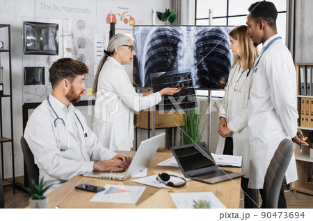 Female specialist explaining x ray result for team in clinic Female specialist explaining x ray result for team in clinic 90473694