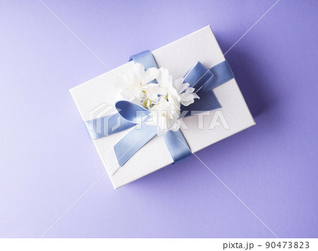 White gift box wrapped with blue ribbon and decor flowers White gift box wrapped with blue ribbon and decor flowers 90473823