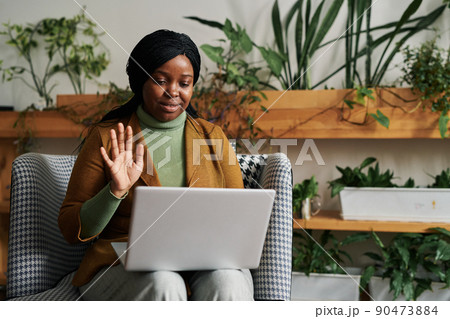 Happy young black woman waving hand to patient during online session Happy young black woman waving hand to patient during online session 90473884