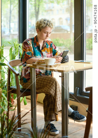 Young female in casualwear holding smartphone by myoelectric hand 90474168